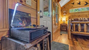 L’intérieur d’un chalet en bois, avec une platine vinyle, des murs en bois, une porte et une fenêtre.