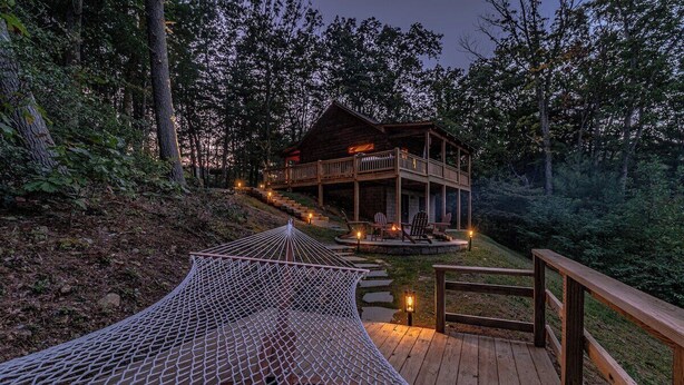 Une terrasse en bois avec un hamac, un espace de terrasse couvert et un bâtiment doté d’un balcon.
