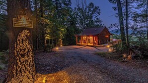 Une cabane avec un chemin de gravier menant à l’entrée, entourée d’arbres.
