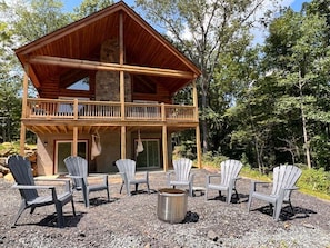 Une cabane en rondins à deux étages, dotée d’un balcon et entourée d’arbres.