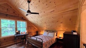 Ein Schlafzimmer mit Bett, Schreibtisch und Fenster.