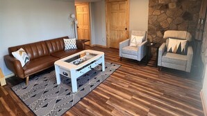 Ein Wohnzimmer mit braunem Ledersofa, einem weißen Couchtisch und zwei Sesseln.