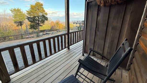 A wooden deck with a bench and railing, overlooking a scenic view of trees and a distant structure. - Farmer`s Market Rm. 102 (Stanardsville)