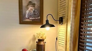 A vintage-style room with a wooden cabinet, a wall-mounted lamp, and a framed picture. - Farmer`s Market Rm. 102 (Stanardsville)