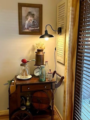 A vintage-style room with a wooden cabinet, a wall-mounted lamp, and a framed picture. - Farmer`s Market Rm. 102 (Stanardsville)