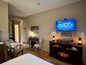 A room with a bed, a television, a fireplace, and two chairs. - Farmer`s Market Rm. 102 (Stanardsville)