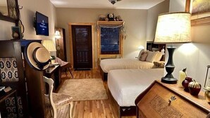 A bedroom with a bed, a desk, a chair, a ceiling fan, and a window with blinds. - Once Upon A Time Rm. 103 (Stanardsville)