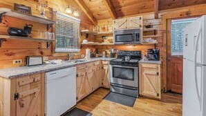 Une cuisine de style rustique, avec des éléments en bois, comprenant une cuisinière, un four à micro-ondes et un lave-vaisselle blanc.