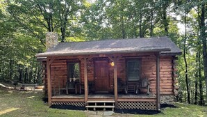 Une cabane en rondins avec un porche, une cheminée et une porte.