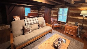 Interior acolhedor de uma cabana de madeira, com um sofá, móveis de madeira e uma lareira.