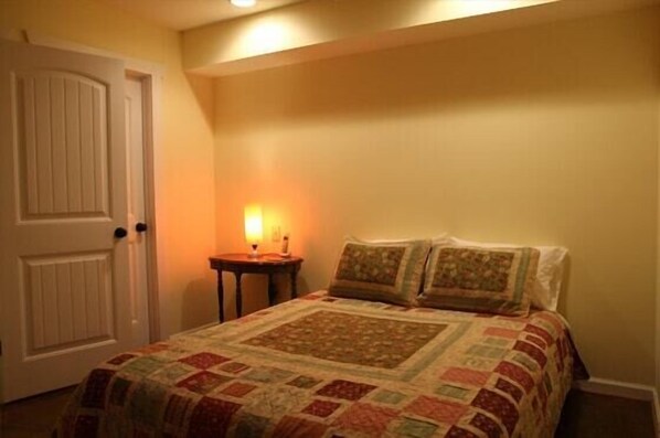Une chambre à coucher avec un lit, une table de chevet avec une lampe et une porte.