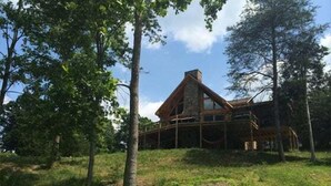 Ein rustikales Blockhaus mit geneigtem Dach, umgeben von Bäumen.