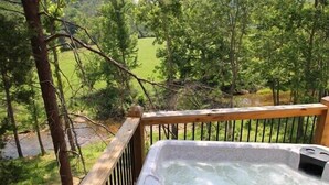 Ein Whirlpool auf einer Holzterrasse mit Blick auf einen bewaldeten Bereich.