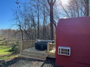 A red RV with a wooden deck and a hot tub.