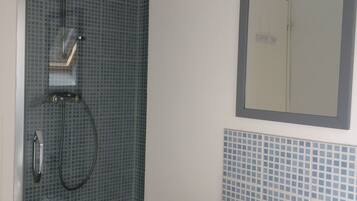 Une salle de bain avec une douche, un lavabo et un miroir.