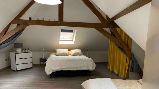 Ein Schlafzimmer mit Schlafkoje, Nachttisch, Beistelltisch und einem Fenster mit Vorhängen.