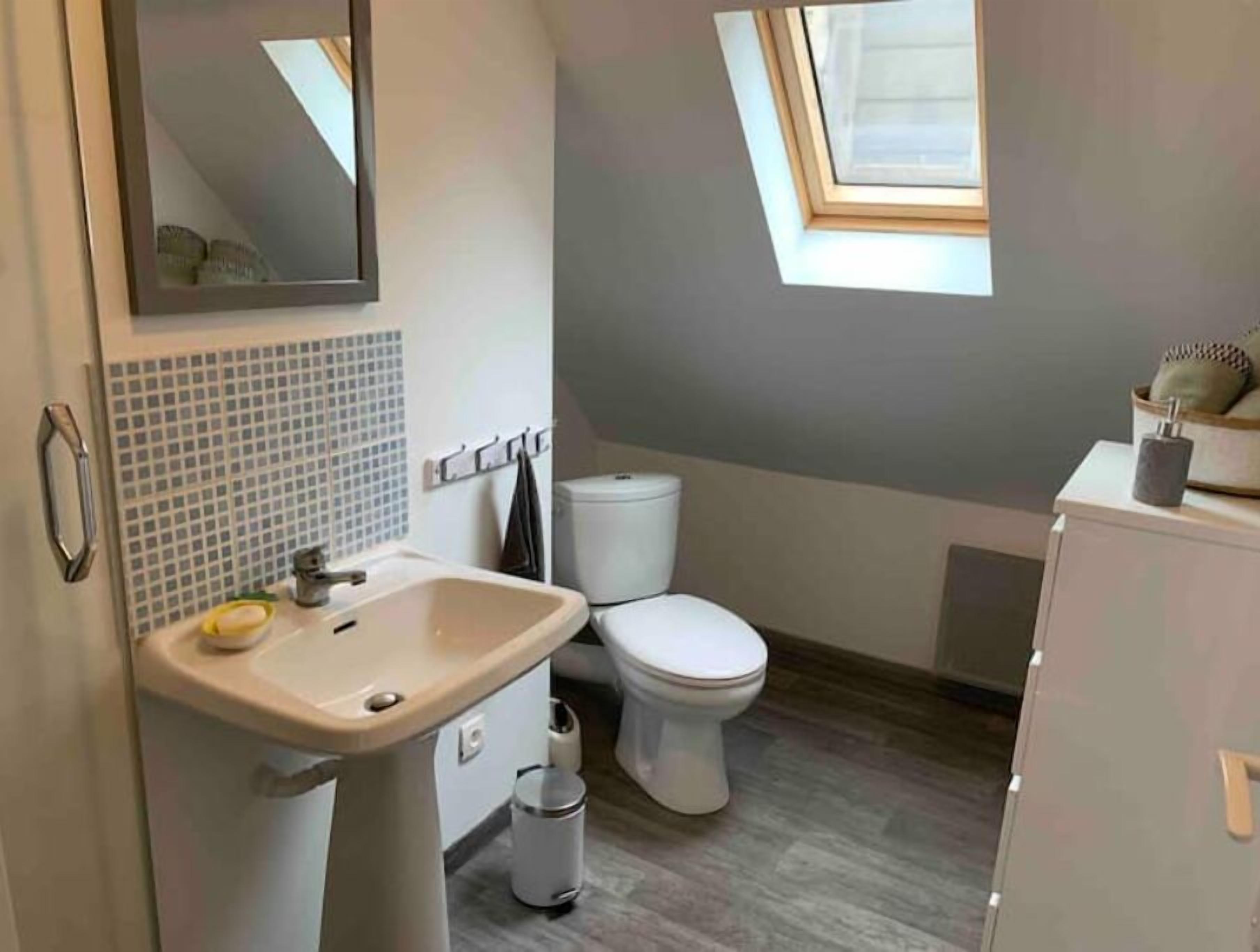 A bathroom with a sink, toilet, and a small window.