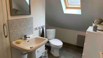 A bathroom with a sink, toilet, and a small window.