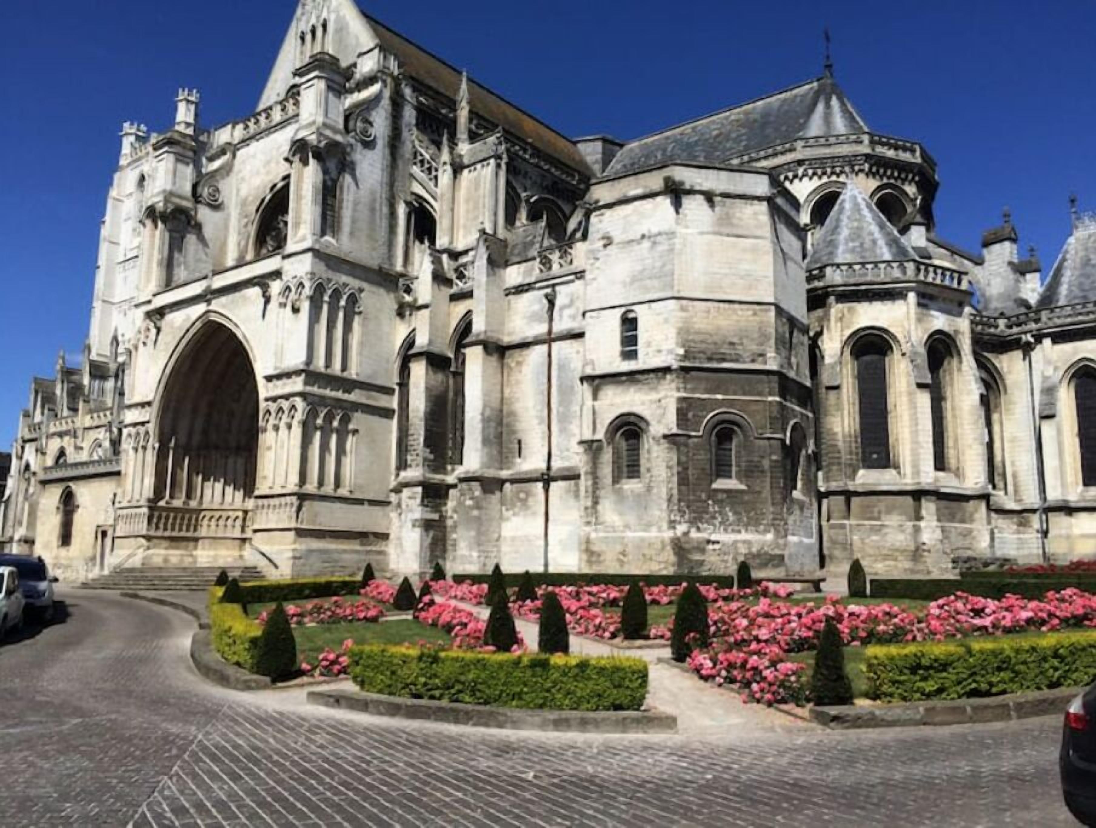 Un bâtiment historique doté d’une grande entrée en arc de cercle, de sculptures complexes et d’une façade symétrique.