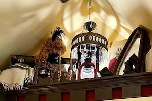 Une pièce avec un lustre, un miroir et un objet décoratif posé sur une étagère.