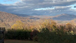 A mountainous landscape with autumn foliage, a bench, and a distant view of a valley. - Empty Arms Parlor - Rm. 208 (Stanardsville)