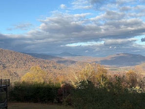 A mountainous landscape with autumn foliage, a bench, and a distant view of a valley. - Empty Arms Parlor - Rm. 208 (Stanardsville)