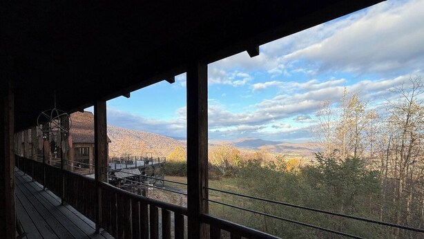A wooden deck with a railing overlooking a mountainous landscape. - Empty Arms Parlor - Rm. 208 (Stanardsville)