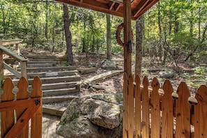 A wooden staircase leading into a forested area with a wooden fence and a sign that reads 'WATCH YOUR STEP'. - Bear Paw Mountain Cottage (Stanardsville)