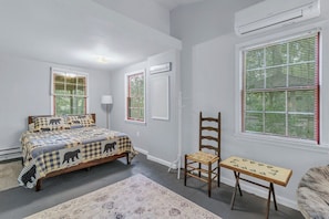 A bedroom with a bed, a chair, a small table, and a window with blinds. - Bear Paw Mountain Cottage (Stanardsville)