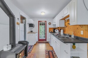 A compact kitchen with white cabinets, a black stove, and a wooden door.