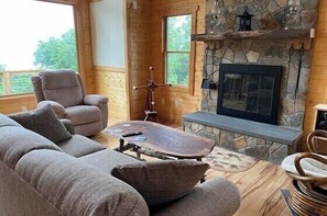 Una sala de estar acogedora con chimenea de piedra, un sofá cómodo y una mesa de centro de madera.