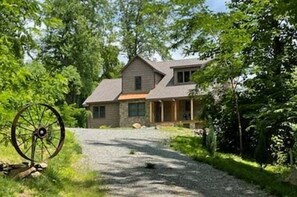 A house with a gravel driveway, surrounded by trees.