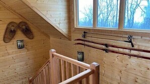 Ein Holzinnenraum mit Treppe, Holzwänden und einem Fenster mit Blick auf Bäume.