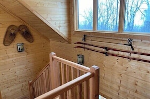 Un intérieur en bois avec un escalier, des murs en bois et une fenêtre donnant sur des arbres.