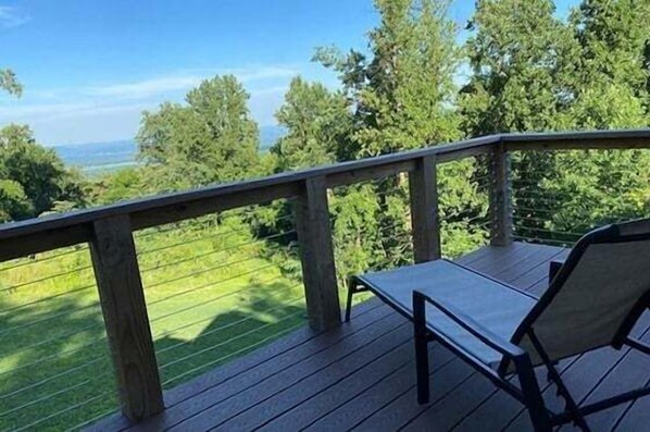 Una terraza de madera con barandilla, una mesa y dos sillas.
