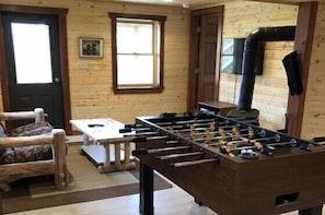 A wooden interior with a foosball table, a sofa, and a fireplace.