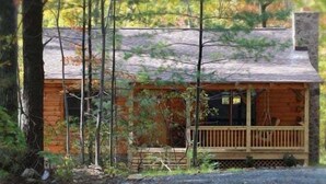 A wooden cabin with a porch, surrounded by trees. - Southern Comfort Cabin (Stanardsville)