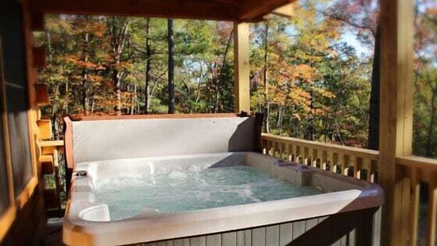 A hot tub in a wooden deck with a view of autumn trees. - Southern Comfort Cabin (Stanardsville)