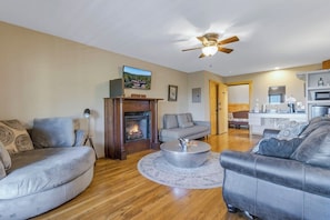 A living room with a fireplace, sofas, a coffee table, and a ceiling fan. - Hollywood Suite - Rm. 204 (Stanardsville)