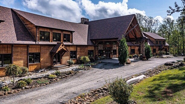 A large log cabin with a central entrance, multiple windows, and a gravel driveway. - Hollywood Suite - Rm. 204 (Stanardsville)