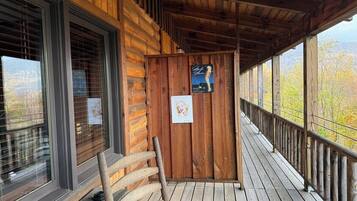 Una cabaña de madera con un porche, una mecedora y vistas a árboles otoñales.
