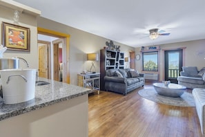 A modern kitchen with granite countertops, a white kettle, and a dining area with a round coffee table.