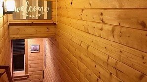Puinen sisustus, jossa on näkyvillä kyltti, jossa lukee ”Tervetuloa”, portaikko ja seinällä oleva kehystetty kuva.