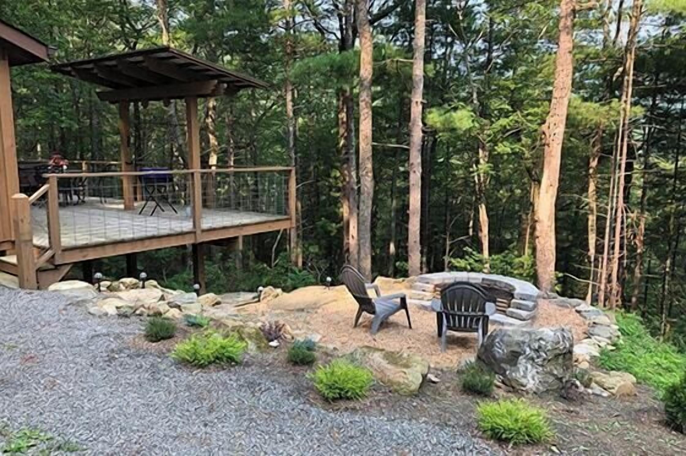 A deck with outdoor seating, a fire pit, and a gazebo in a forested area.
