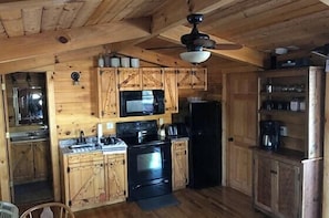 A wooden cabin-style kitchen with a microwave, stove, refrigerator, and wooden cabinets. - Tucked Away Mountain Cabin (Stanardsville)