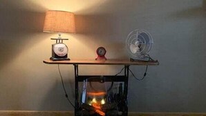 A table with a lamp, a clock, and a fan.