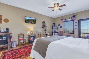 Une chambre à coucher comprenant un lit, un bureau, une chaise, un téléviseur et un ventilateur de plafond.