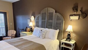 A neatly made bed with a headboard, bedside tables with lamps, a chair, and a sign on the wall.