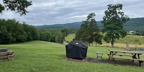 Un espacio al aire libre con una parrilla, mesa de picnic y bancos.