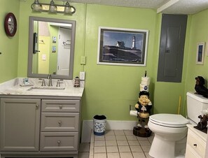 A bathroom with a green wall, a sink with a mirror, a toilet, and a trash can. - Mountain View Farmhouse (Stanardsville)